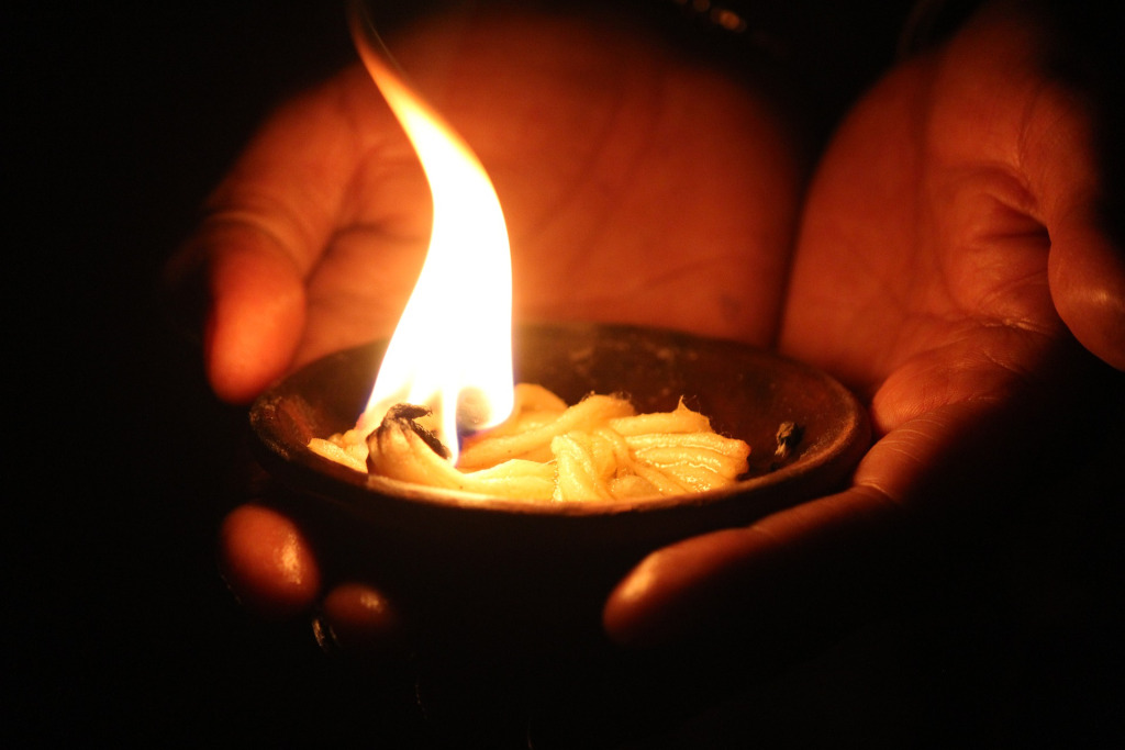 A hand holding a lighted earthen lamp