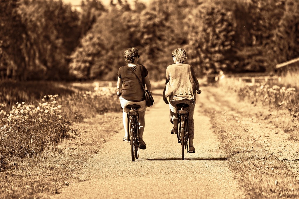 Old sepia photo of two women riding bicycles in the countryside
